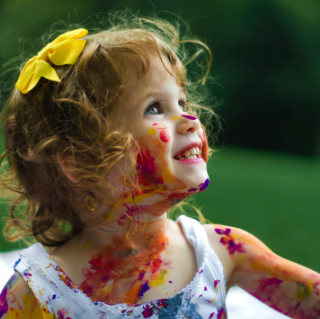 Smiling girl covered in different colour paints