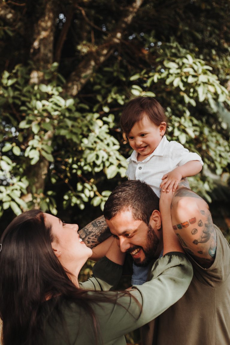 Couple place toddler on dads shoulders smiling