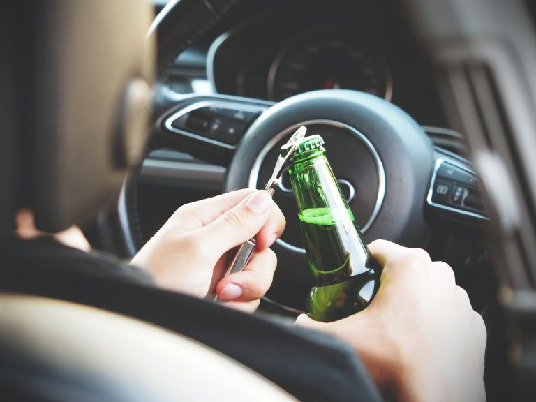Driver opening beer bottle behind the wheel
