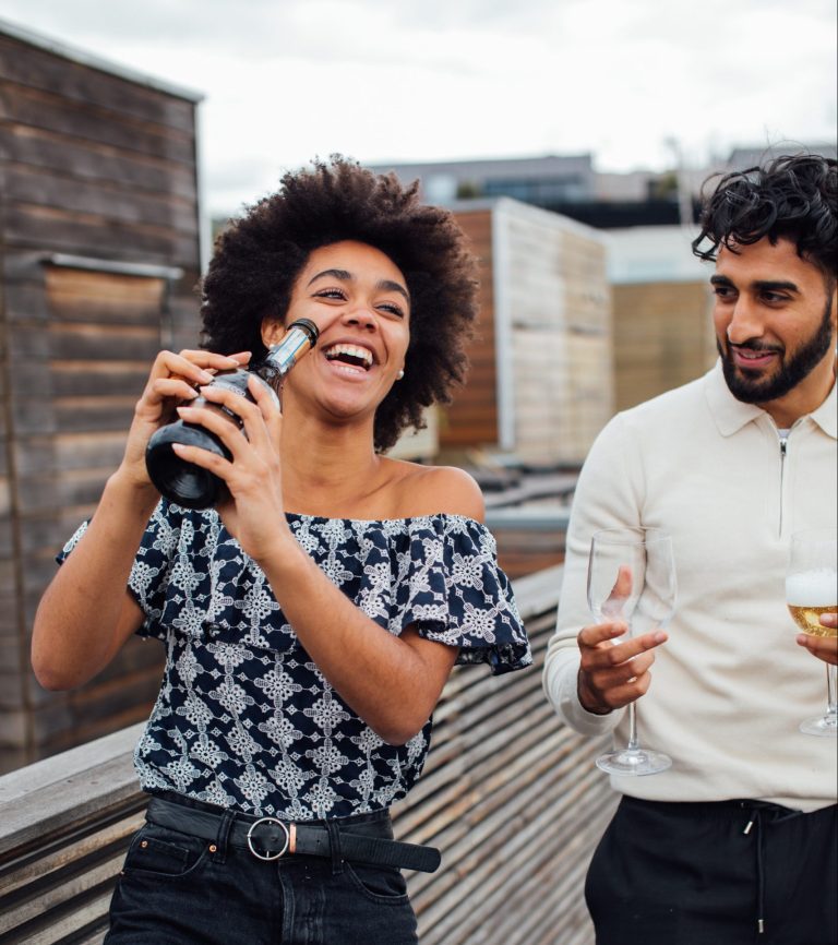 Excited couple celebrate property purchase with champagne on balcony