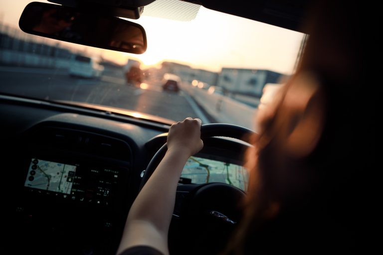 Female driver driving with sunset ahead