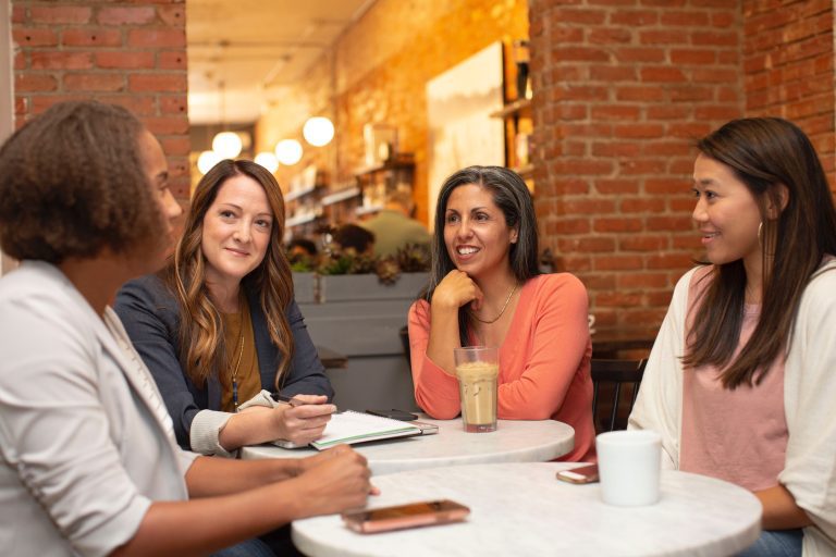 Four women talk around coffee table