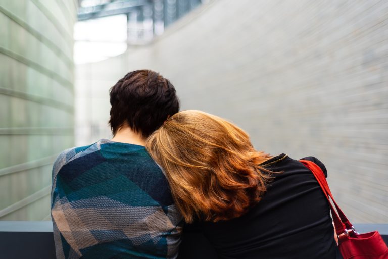 Mom rests head on sons shoulder outdoors