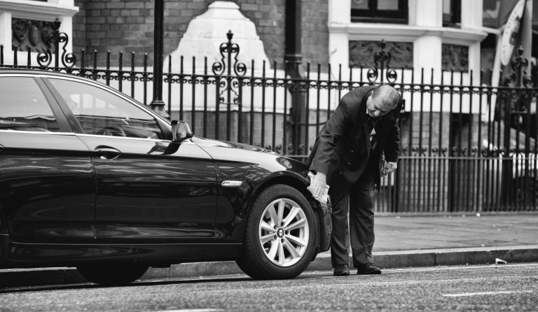 Man checks cars front bumber