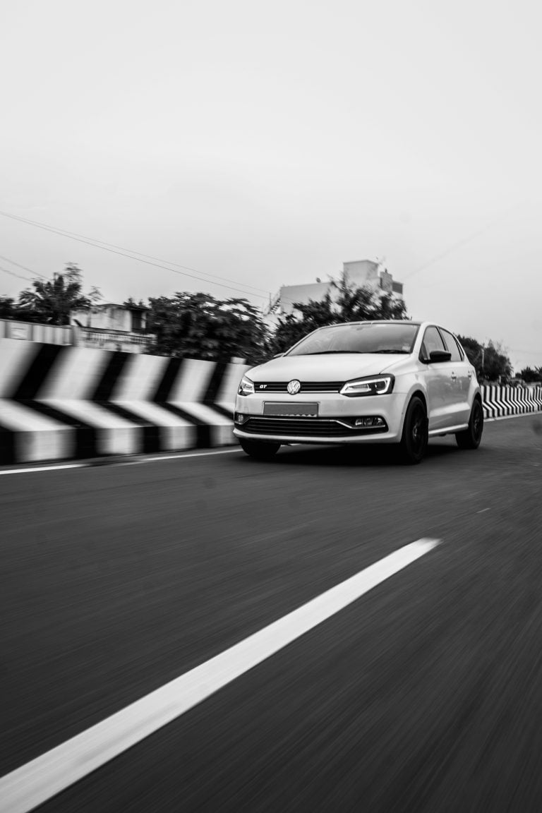 White hatchback car driving on the road