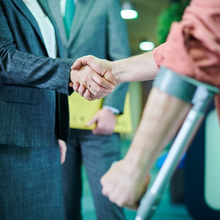 Man using crutches shakes the hand of lawyer