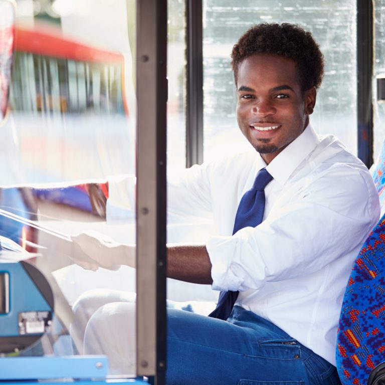 Young bus driver smiles while behind the steering