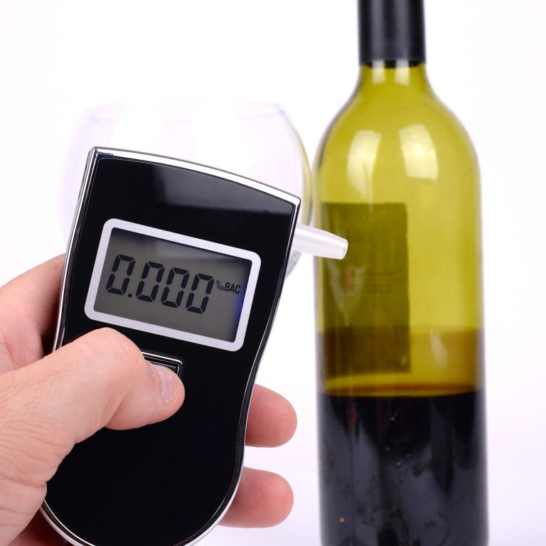 Breath test machine turned on next to half drunk wine bottle