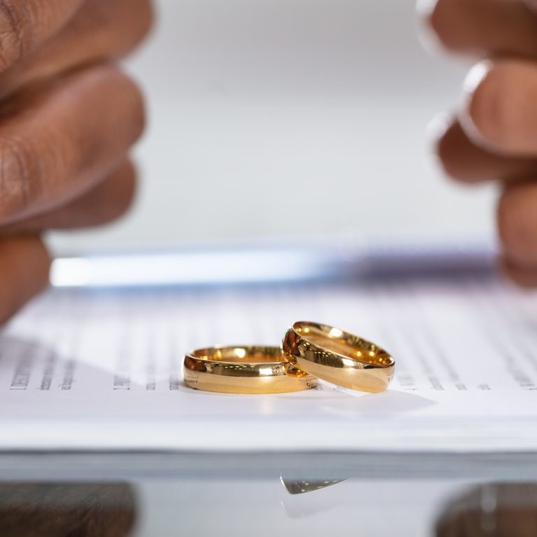 Couple lay their wedding rings down on a divorce and separation document