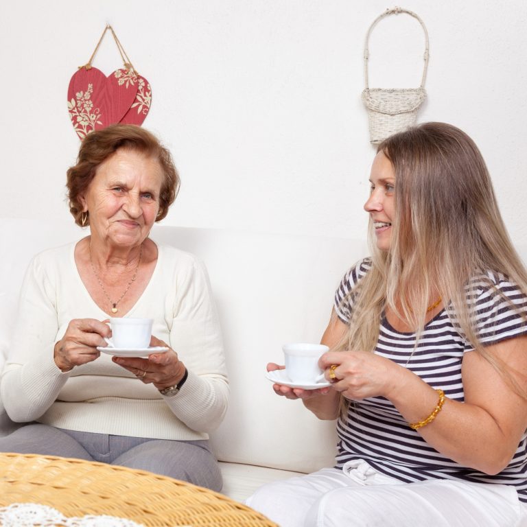 elderly lady enjoys tea with younger lady