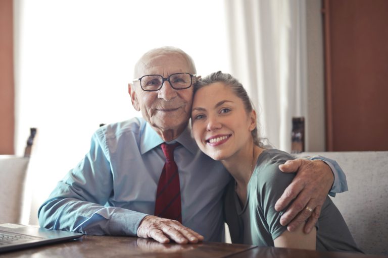 Grandad wraps one arm around his granddaughter