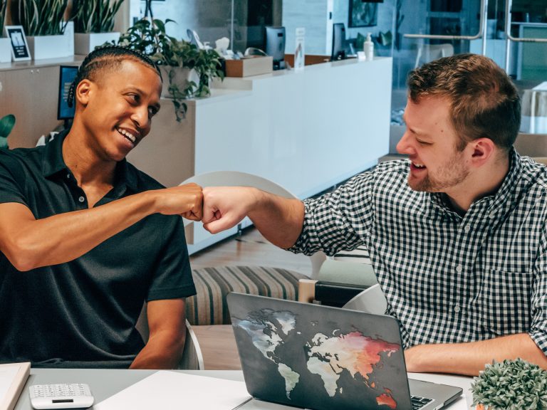 Happy male client fist bumps Scullion LAW road traffic solicitor using a laptop