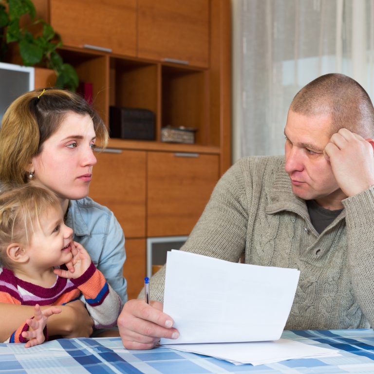 Husband and wife sit at dinner table holding Will with toddler present