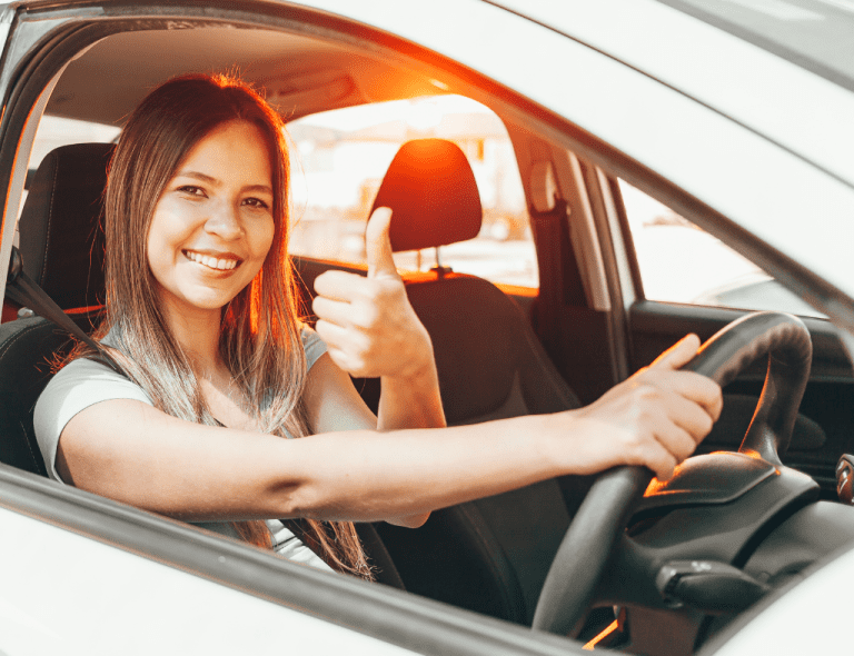 Lady smiles as she holds the steering and gives a thumbs up