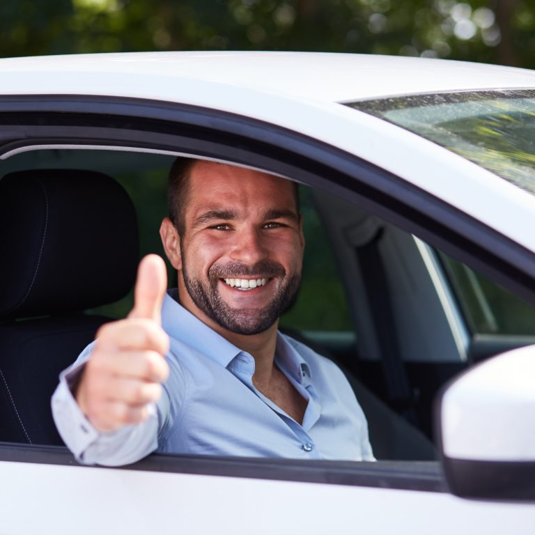 Male driver smiling holding up thumbs up sign