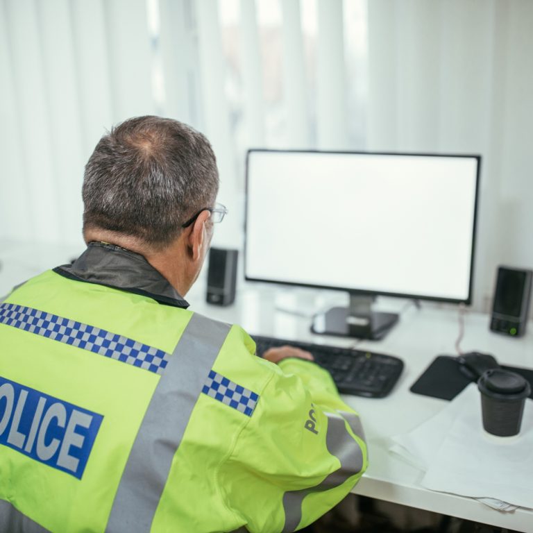 Male police officer watching computer screen