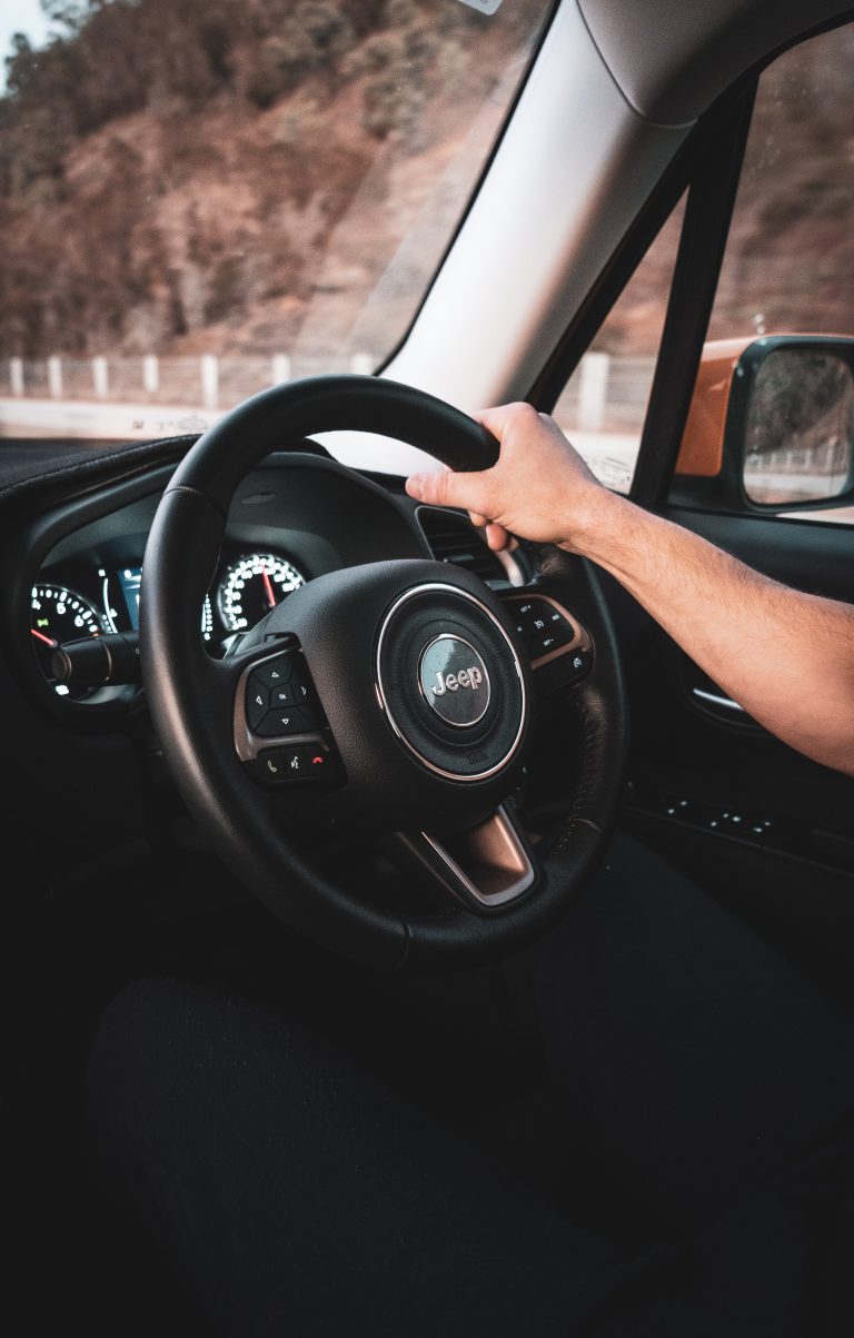 Man driving jeep holding steering with one hand
