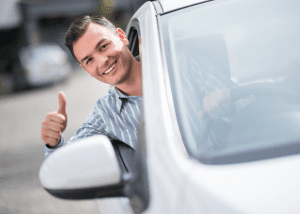 Man leans out of car smiling giving thumbs up