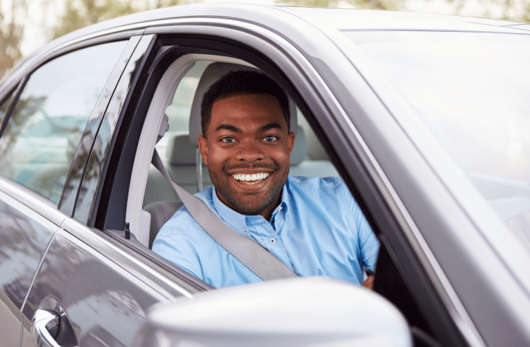 Man wearing blue shirt smiles in drivers seat