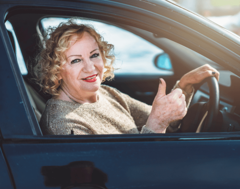 Smiling woman driver raises thumbs up sign