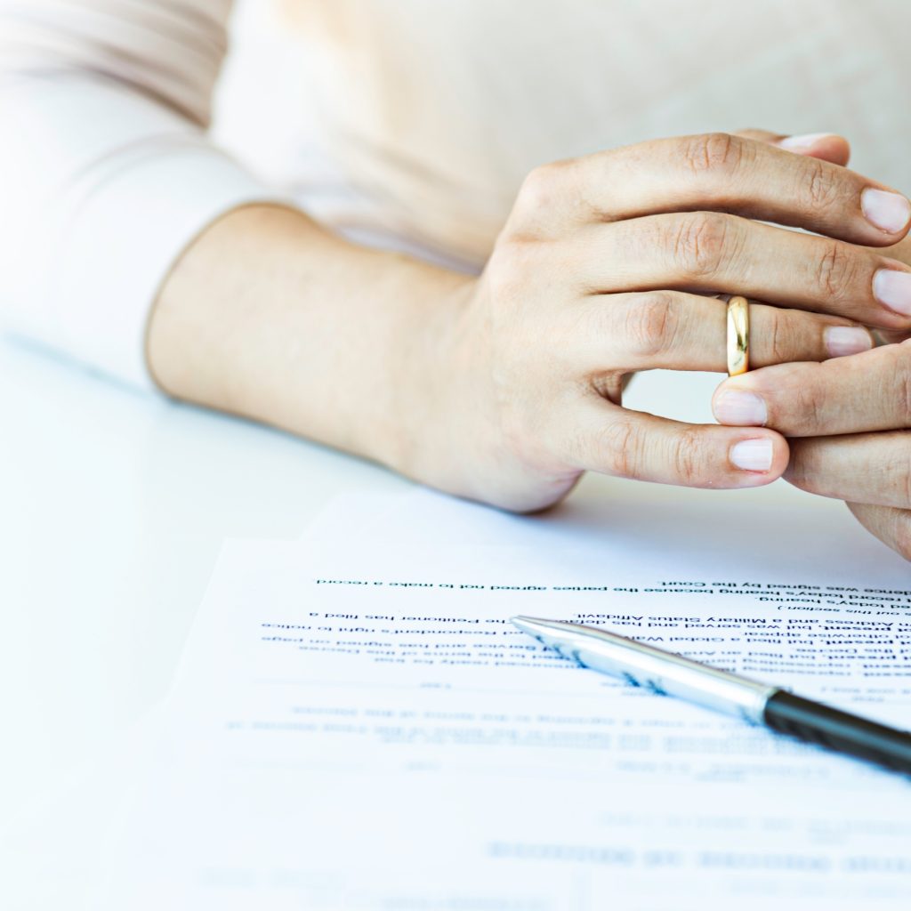 Woman removes wedding ring with cohabitation agreement on the table
