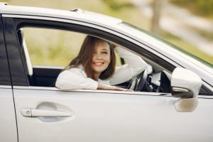 Young woman smiles looking out the window of drivers side door