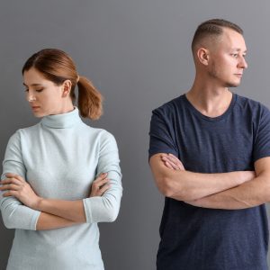 Ccouple stand with arms crossed looking sadle away from each other