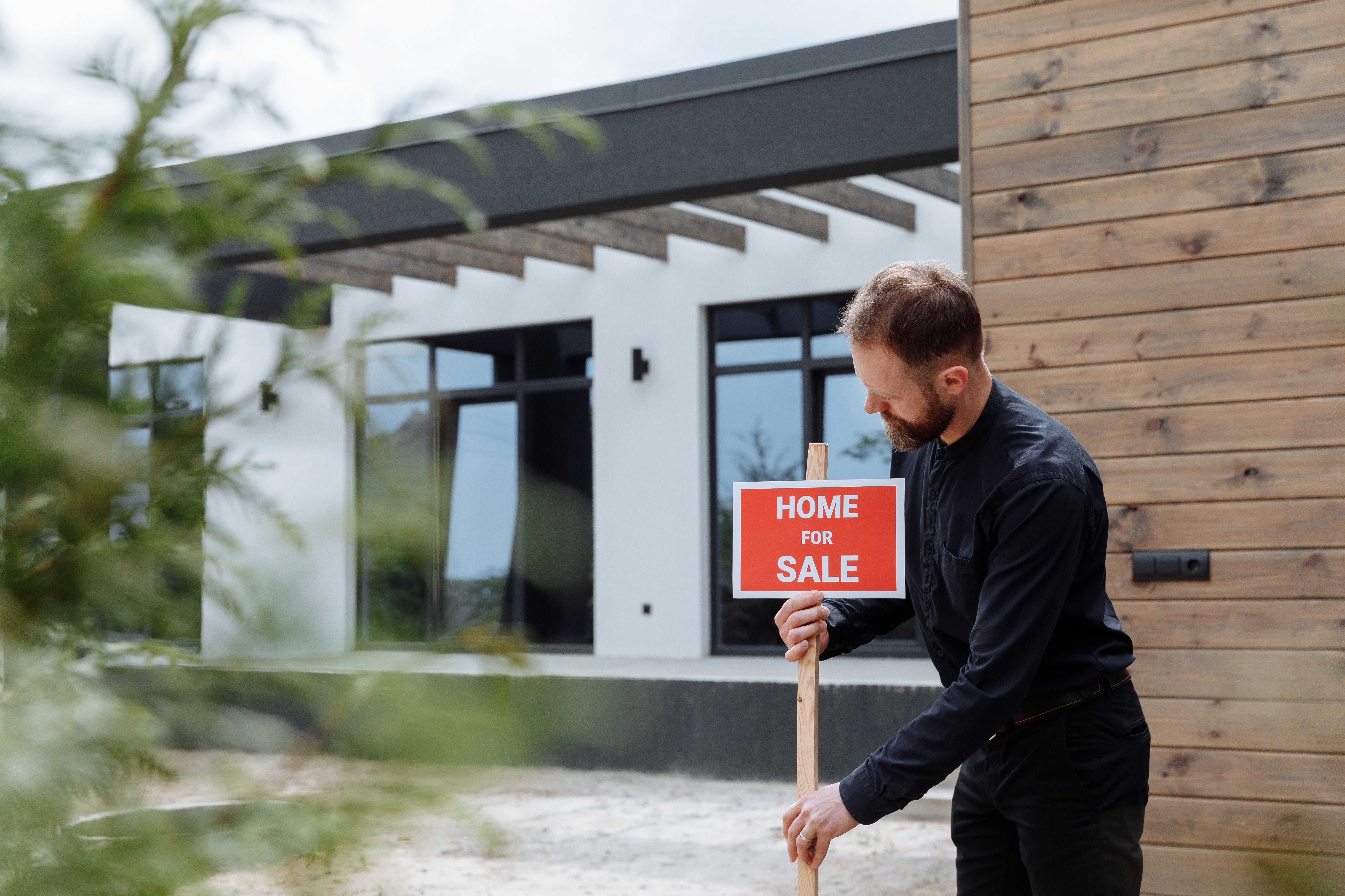 Estate agent installs home for sale sign outdoors