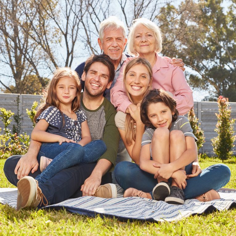 Grandparents children and grandchildren pose happily outdoors