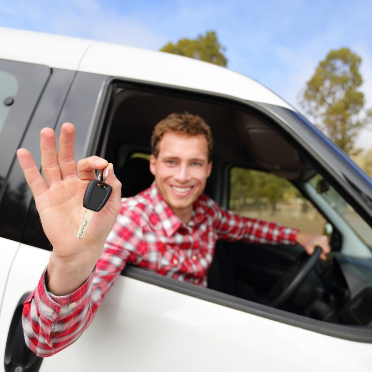 Happy male driver holds out car keys through window