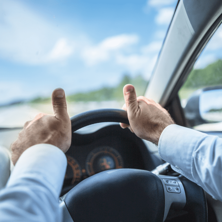 Male driver holds steering with both hands with double thumbs up