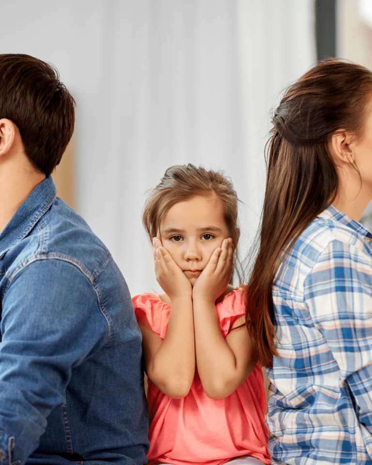 Daughter sits between parents backs clasping her cheeks