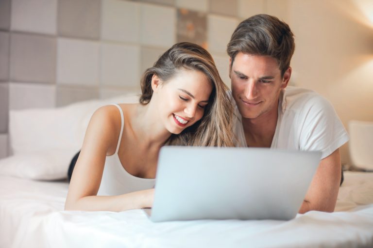 Caucasian couple share smile perusing a laptop