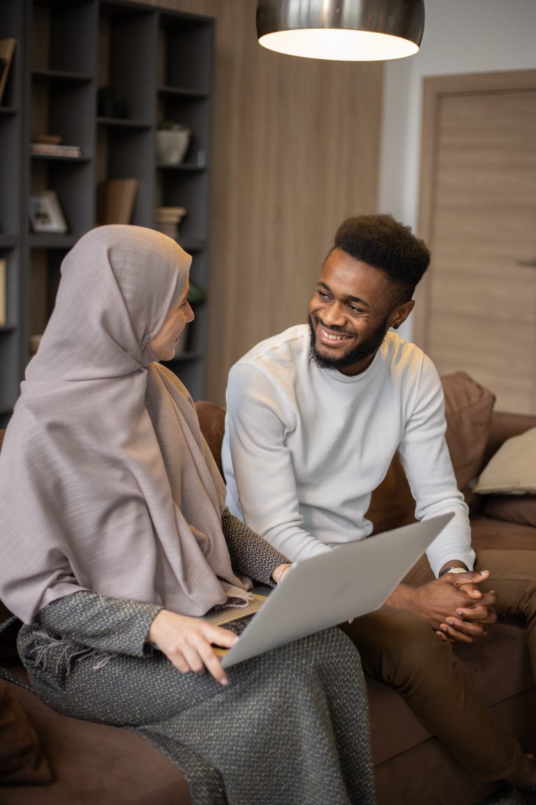 Muslim couple share smile sitting on a sofa