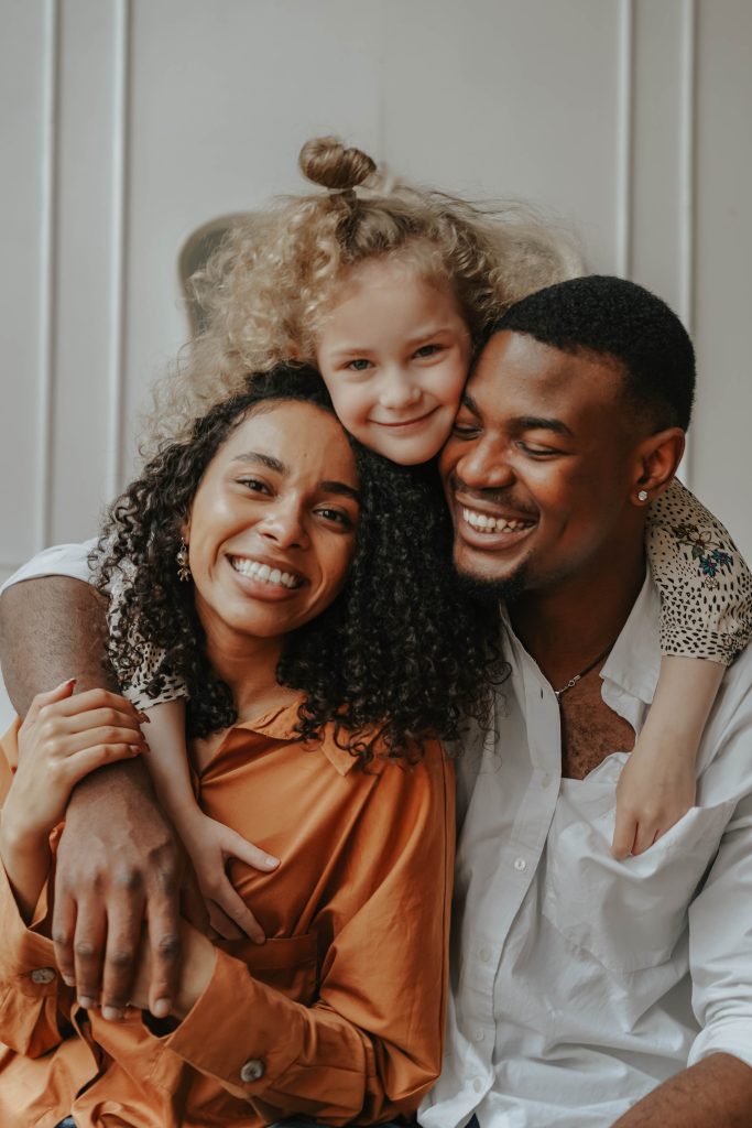 Family of three share smiles as the pose for picture