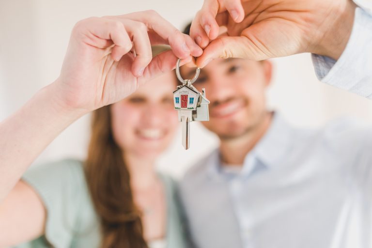 Couple hand over house keys smiling
