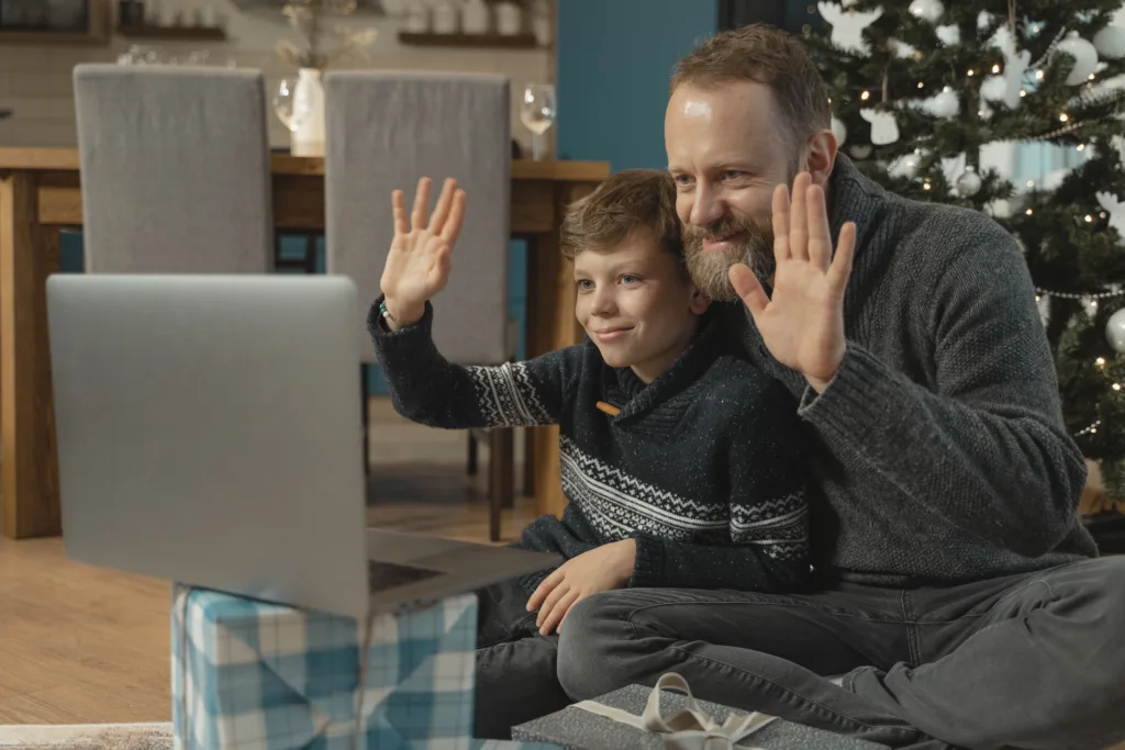 Father and Son wave during video chat on computer for Christmas contact