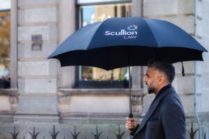 Urfan Dar outside Hamilton office with a Scullion LAW umbrella