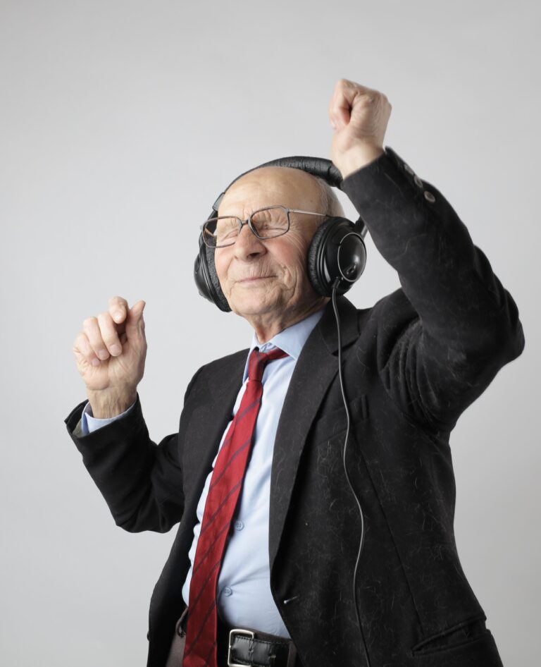 Elderly man in suit dances with headphones on