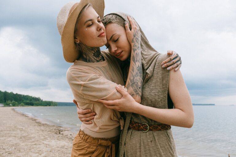 Girl consoles her friend in a hug by the shore