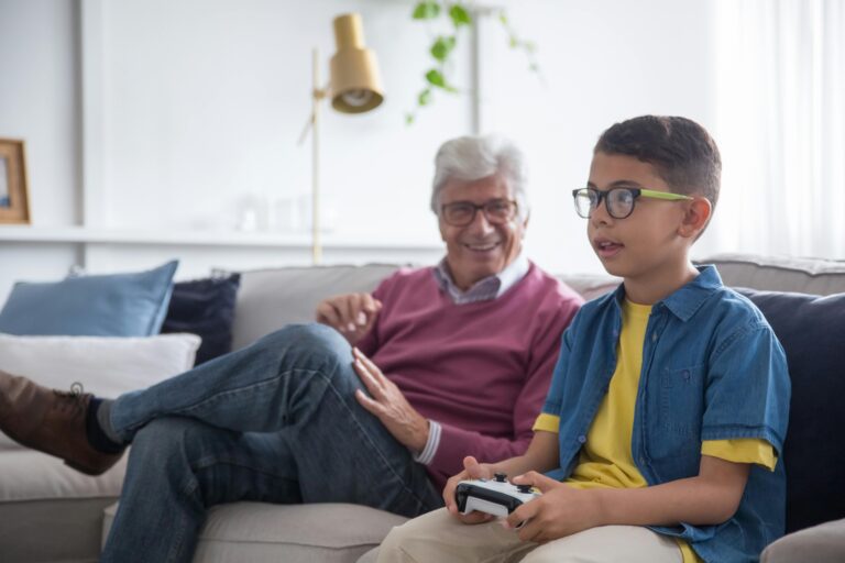 Granddad watches grandson as he plays video game