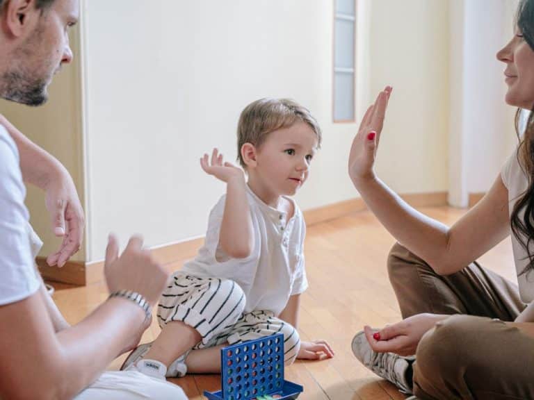 Mother and father playing with their young son on the living room floor, with the mother giving the son a high five, highlighting Scullion LAW's dedication to family well-being.