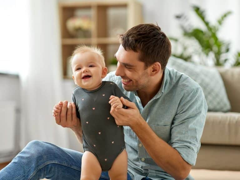 Father guiding his baby as they take their first steps together in the living room, highlighting Scullion LAW's Family Law legal services.