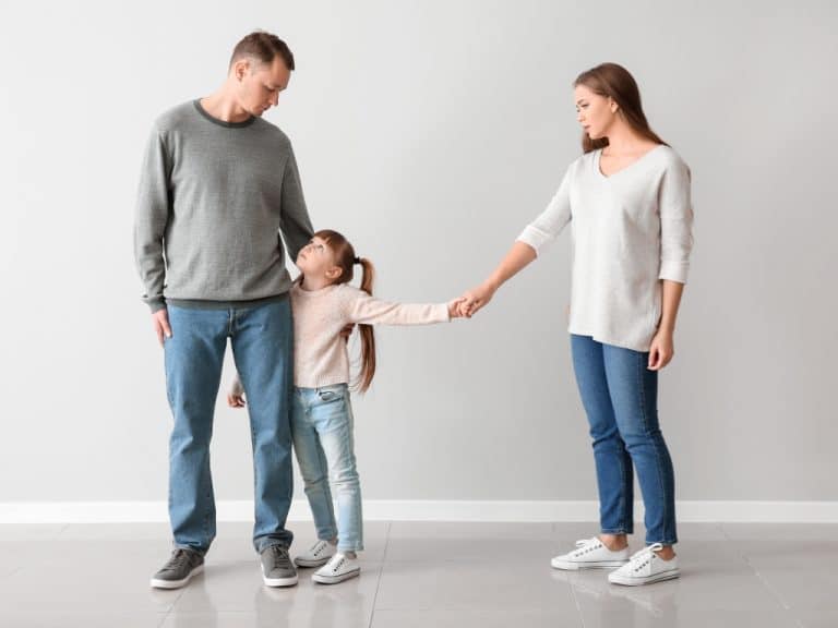 Father stands next to his daughter with arm around her, the daughter looks up to her dad while reaching out to her mum, highlighting Scullion LAW's support in separation and divorce cases.