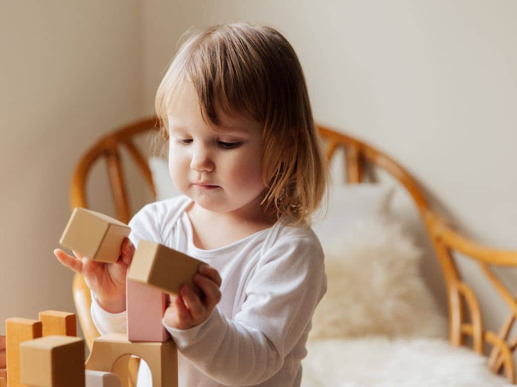 Young child plays with blocks alone in a bright room, highlighting Scullion LAW's expertise in Child Law and Child Maintenance services.