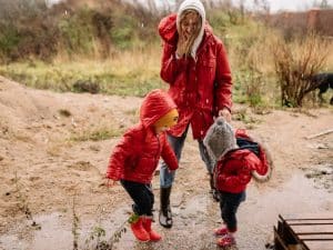 Mother laughing while playing with her two sons in the rain