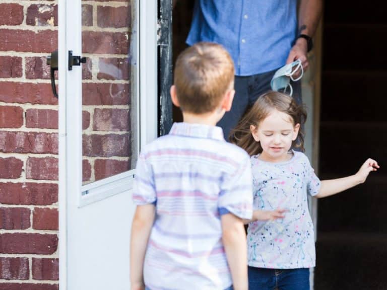 A father collects his two children from their mother. His son and daughter are standing outside the front door as he heads out with them.