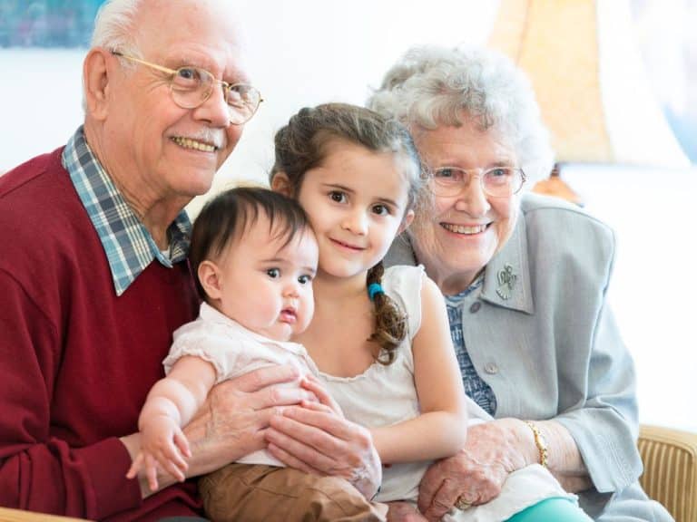 Elderly couple smiling with their grandchildren, seeking future protection with a Will and Power of Attorney from Scullion LAW.