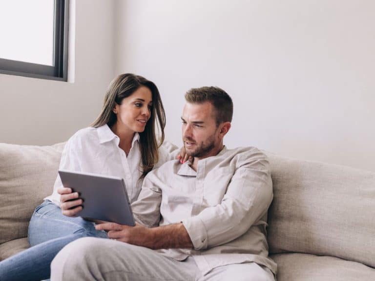 Young couple discussing their Wills and Powers of Attorney with Scullion LAW on their sofa.