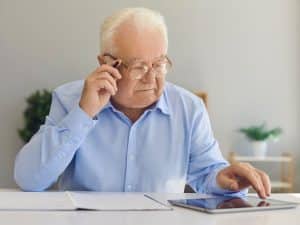 Elderly man at desk reviewing his Will and Power of Attorney with Scullion LAW, ensuring his family's future is secure.